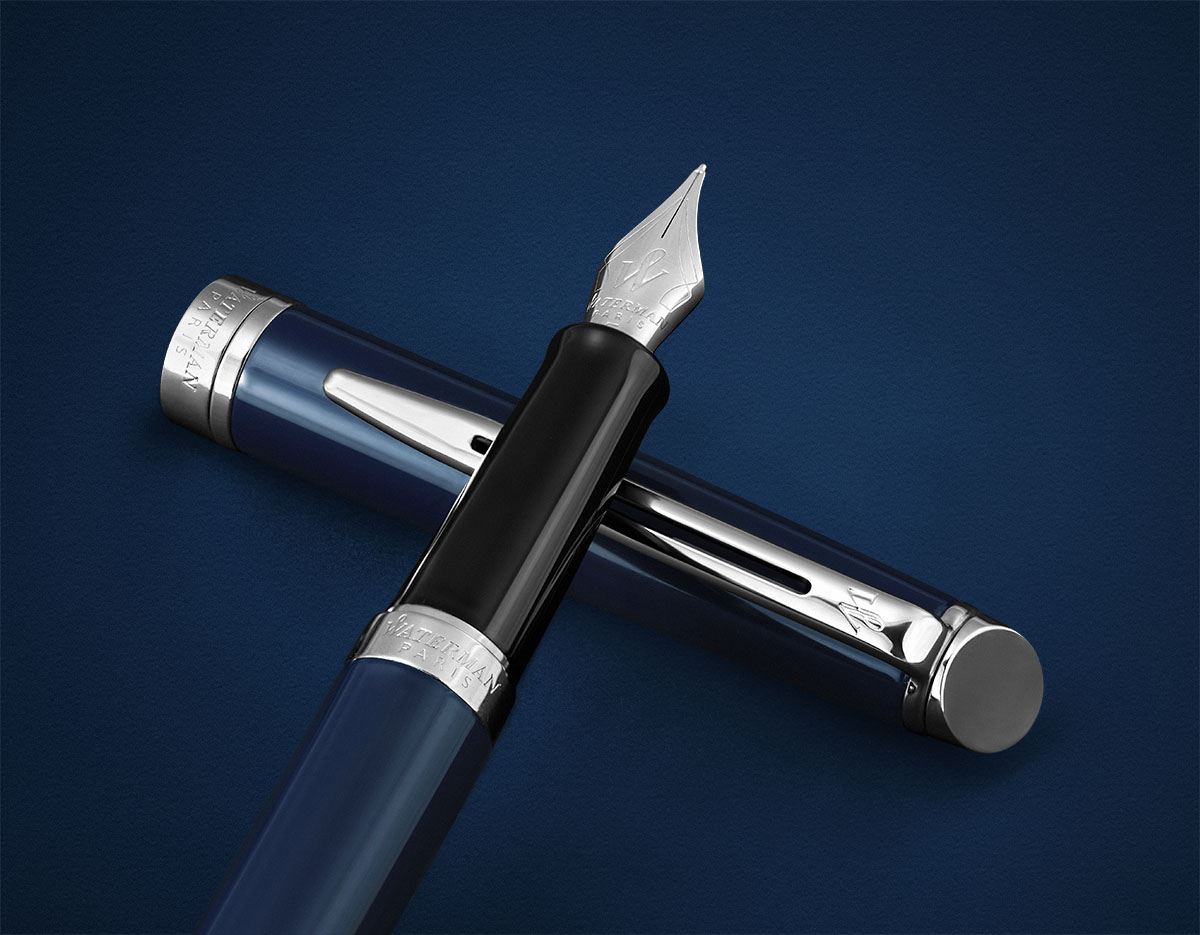 Eleganckie pióro wieczne Waterman w kolorze granatowym ze srebrnymi wykończeniami na tle w odcieniu granatu.